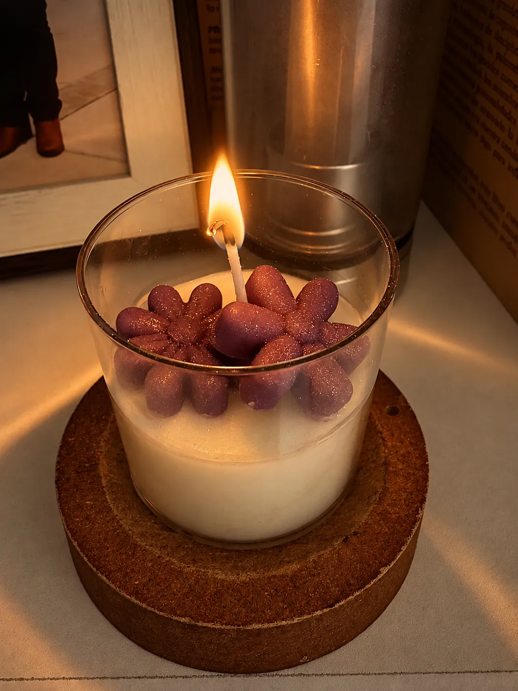 Vela encendida en vaso con flores de cera